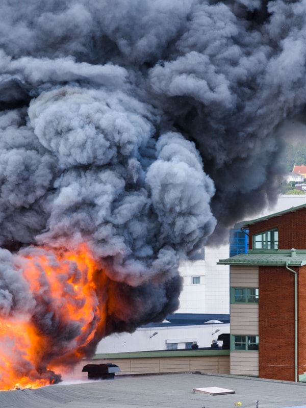 Sort røyk og flammer som stiger opp fra en bygning
