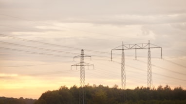 Strømmaster og strømledninger med solnedgang i bakgrunnen