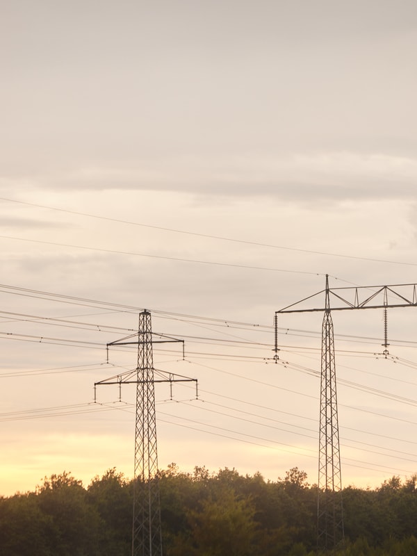 Strømmaster og strømledninger med solnedgang i bakgrunnen