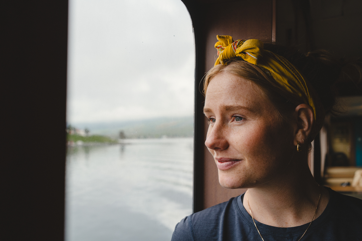 Ung kvinne med tørkle på hodet som ser ut av et vindu