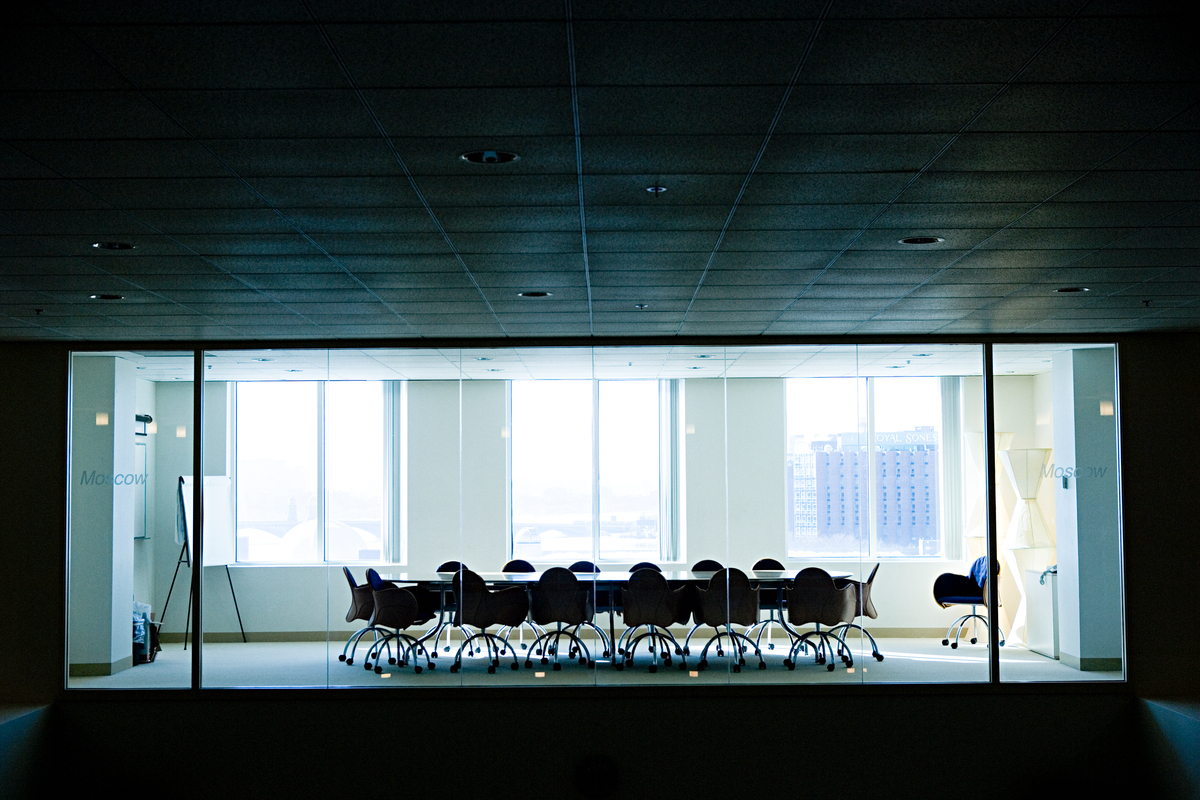 Mørkt møterom med møtebord og tomme stoler.