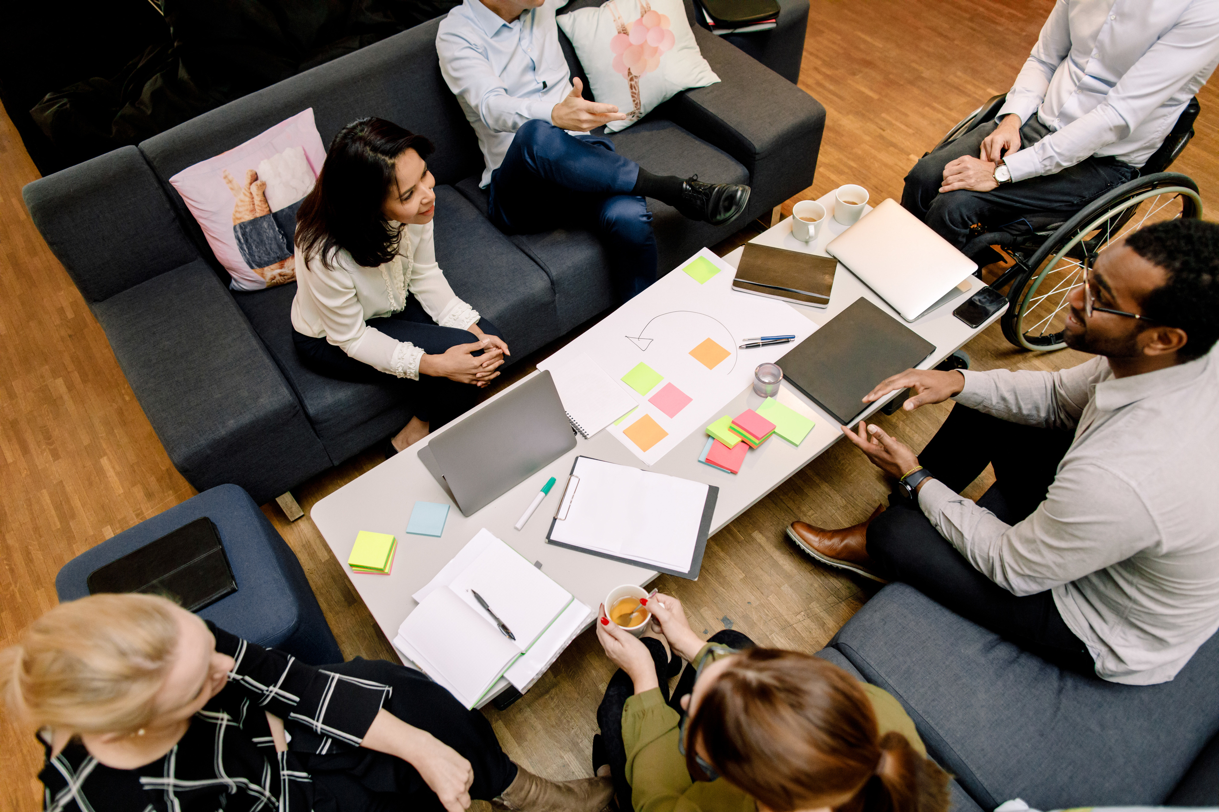Kollegaer sitter rundt et bord med papirer og lapper i ulike farger.