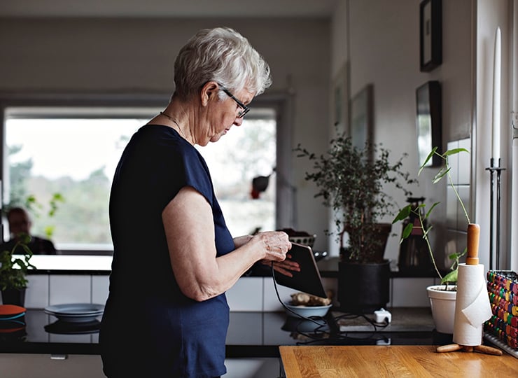 Kvinne på kjøkken som setter ipad til lading