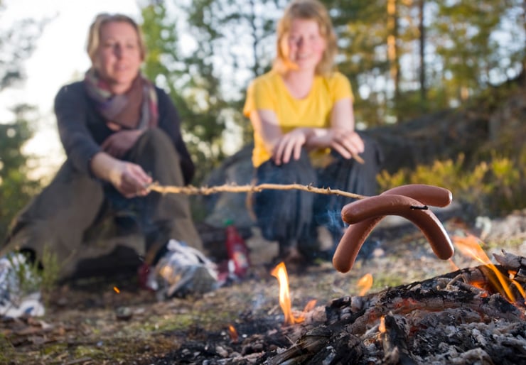To personer som sitter ved et bål i skogen.