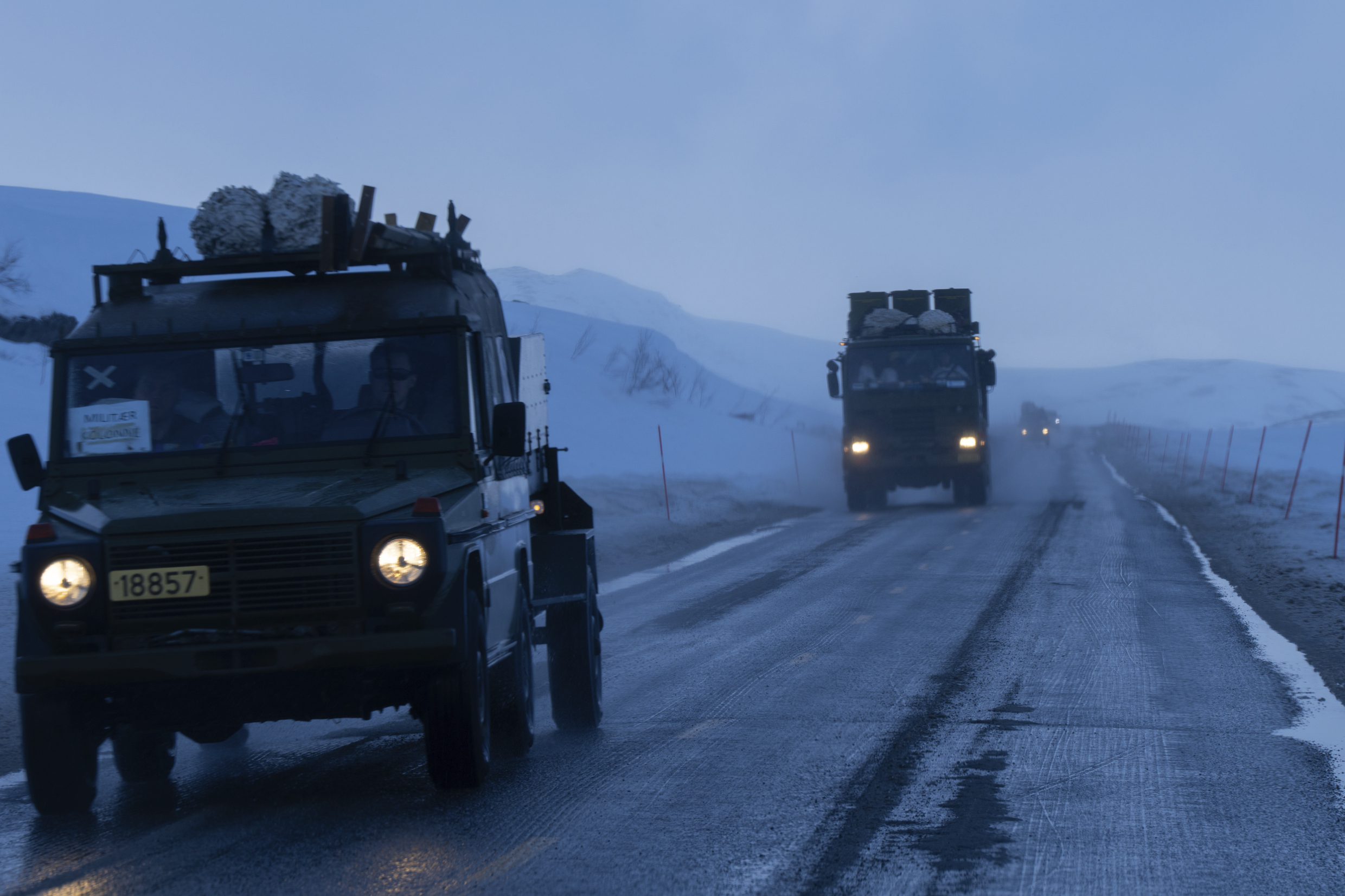 Militære kjøretøy på vei i vinterlandskap under øvelse